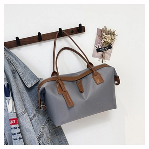 Detailed view of gray tote bag with brown leather handles hanging on a wall hook