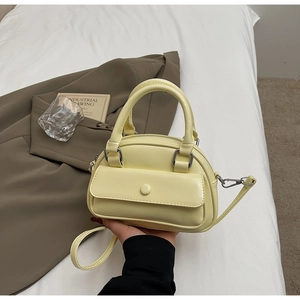 Detail of light yellow leather pillow bag showing the front flap pocket and silver hardware