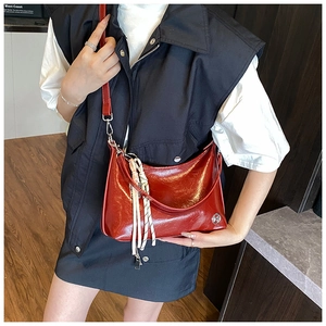 Detail of red oil wax leather shoulder bag with woven pendant and glossy finish