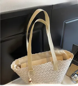 Detail of hollow woven straw tote bag with wood bead tassel and interior pocket