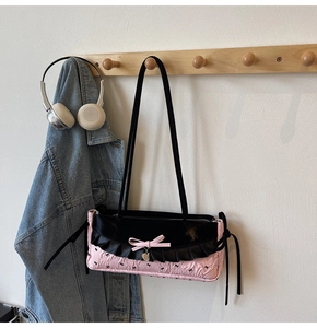 Détail du sac à bandoulière rose et noir avec volants et pendentif en cœur