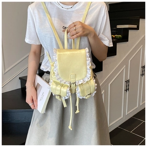 Detail of pale yellow PU leather backpack with delicate white lace trim and magnetic flap