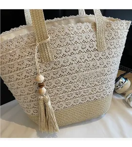 Detail of hand-woven straw tote with hollow lace pattern and decorative wooden bead tassels