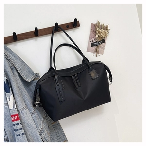 Detail of a black nylon tote bag hanging on a hook with a leather logo tag