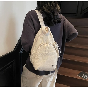 Detail of beige nylon crossbody bag with textured fabric and drawstring pocket