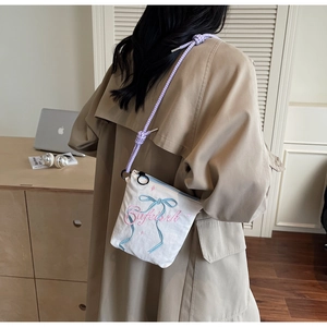 Detailed embroidery of blue bow and pink script on white canvas crossbody bucket bag