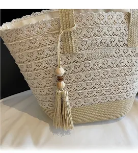Detail of hand-woven straw tote with lace patchwork and bohemian tassel ornament