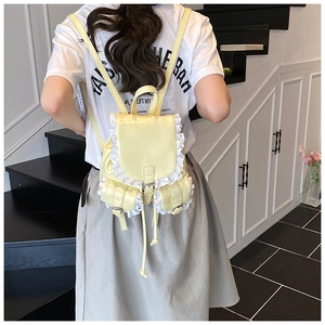 Rear view of model carrying a pale yellow lace-trimmed backpack with multi-pocket detail
