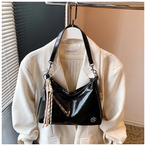 Detail of glossy oil wax leather shoulder bag with woven tassel and metal logo