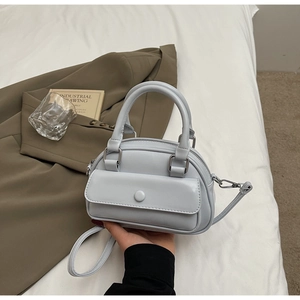 Close-up of light blue leather Boston bag with round metal buckle and silver zipper detail