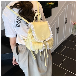 Detail of cream yellow PU leather backpack with delicate white lace trim on the flap