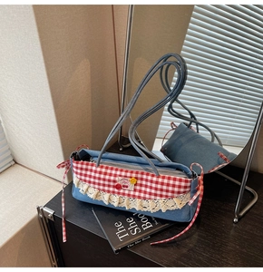 Détail du sac bandoulière en denim bleu avec rabat à carreaux rouges et dentelle