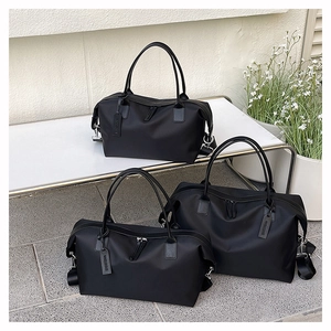 Three black waterproof nylon tote bags with leather handles on a minimalist metal bench