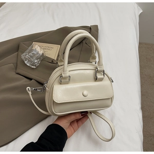 Detail of creamy white PU leather pillow bag with silver hardware and detachable strap