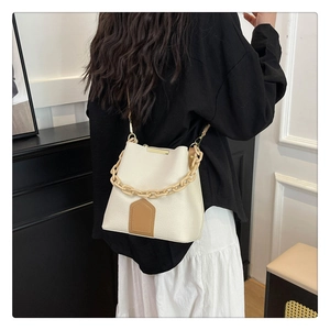 Détail du sac seau en cuir grainé blanc cassé avec chaîne jaune et empiècement brun