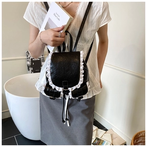 Detail of black glossy PU backpack with intricate white lace trim in a vintage Lolita style
