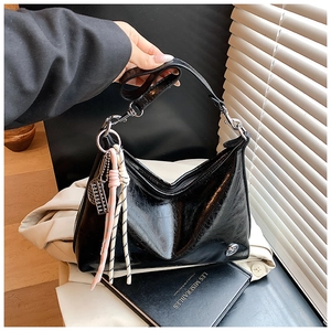 Detail of black oil wax leather shoulder bag with decorative pink woven rope and metallic charm