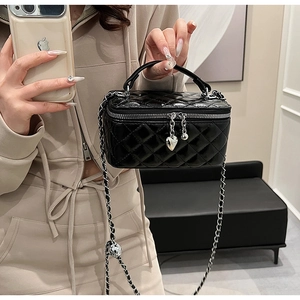 Detail of black quilted mini vanity bag featuring heart zipper and leather chain strap