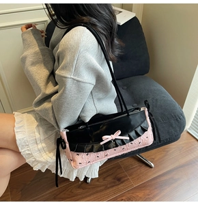 Détail du nœud rose et du tissu jacquard papillon sur un sac sous le bras noir