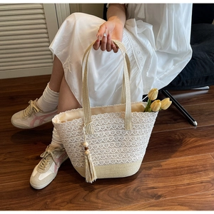 Close-up of handmade lace tote bag with straw base and wooden bead tassel detail