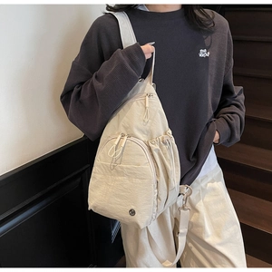Close-up of beige nylon crossbody chest bag with adjustable strap on a model