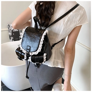 Detailed view of a black PU leather backpack with vintage white lace crochet trim accents