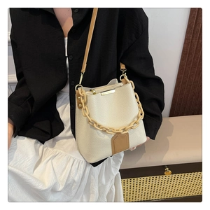 Détail du sac seau blanc cassé avec cuir grainé et bandoulière en chaîne acrylique