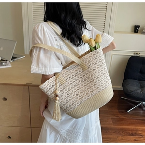 Detail of straw tote bag featuring white floral lace overlay and side tassel decoration
