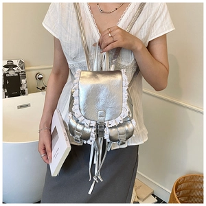 Detail of silver faux leather backpack featuring white lace trim and double front pockets