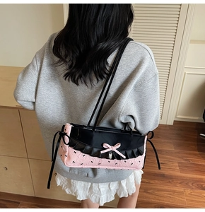 Vue détaillée de l'arrière du sac à bandoulière rose et noir avec détails de nœuds