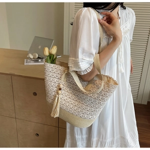 Detailed close-up of woven lace tote bag with straw base and wood bead tassel decoration