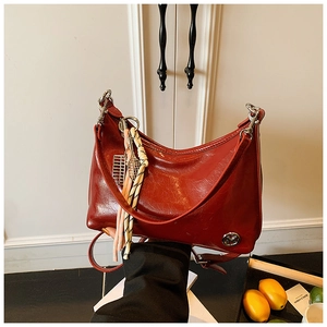 Detail showing vintage red oil wax leather shoulder bag with tassel and tennis racket charm
