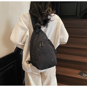 Detail of adjustable strap and multi-pocket design on a sleek black nylon crossbody bag