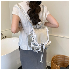 Silver backpack with white lace trim and metallic finish shown on model's back