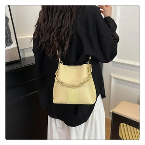 Vue détaillée du sac seau crème avec chaîne et texture litchi porté par le modèle