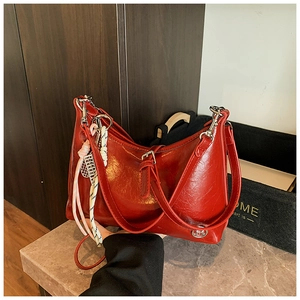 Detail of vintage red oil wax leather hobo bag with round metal logo and braided charm