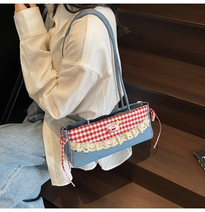 Détail du sac à bandoulière en denim bleu avec vichy rouge, dentelle et patch cerise