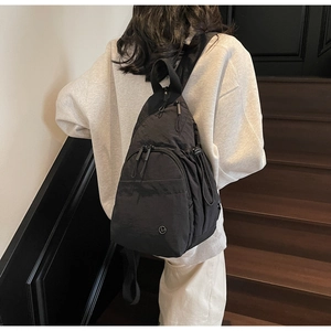 Detail of black nylon crossbody bag with zipper compartments and a round logo
