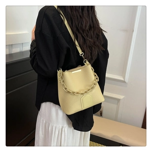 Détail du sac seau crème avec cuir texturé et bandoulière élégante en chaîne dorée