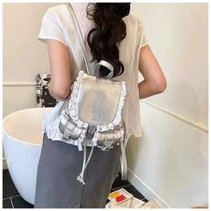 Detail of silver metallic backpack with white lace trim and dual front buckle pockets