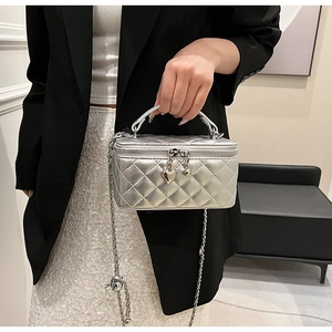 Close-up of silver quilted mini bag with chain strap and heart-shaped metal charms