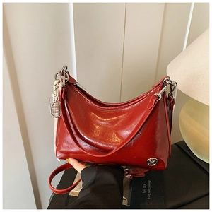 Detail of red glossy oil wax leather hobo bag with silver logo and tennis racket charm
