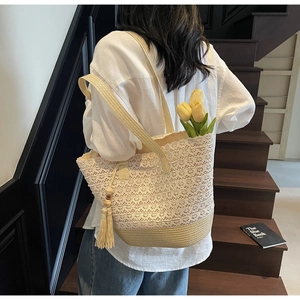 Close-up of beige lace crochet tote with woven straw base and tassel detail