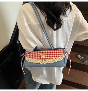 Détail du sac sous l'aisselle en denim avec surpiqûres à carreaux et broderie cerise