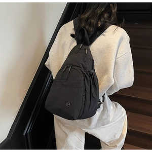 Detail view of a black nylon backpack on model showing minimalist urban style and metal logo