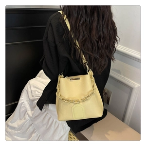 Détail du sac seau jaune en cuir grainé avec poignée chaîne et bandoulière fine