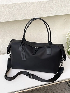 Minimalist black nylon tote bag with top handles and adjustable shoulder strap