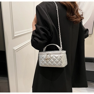 Detailed shot of a silver quilted handbag with heart charm and metal chain strap