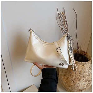 Close-up of cream oil wax leather crescent bag with silver buckle and tassel detail