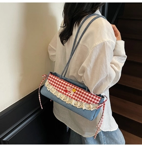 Détail du sac à bandoulière en denim avec rabat vichy rouge et bordure en dentelle blanche